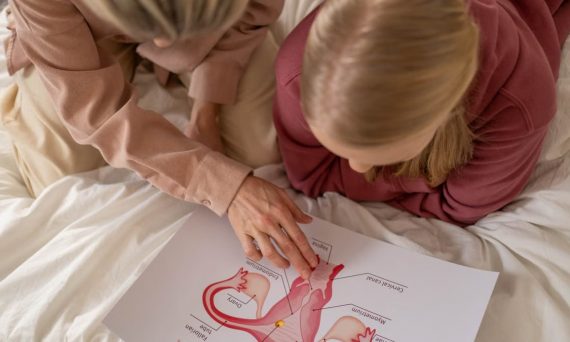 Mother and daughter studying reproductive system illustration for sex education at home.